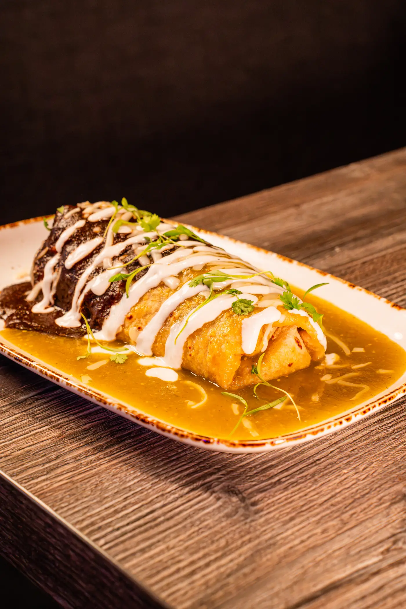 Wet burrito half mole half salsa verde with crema drizzle and cilantro