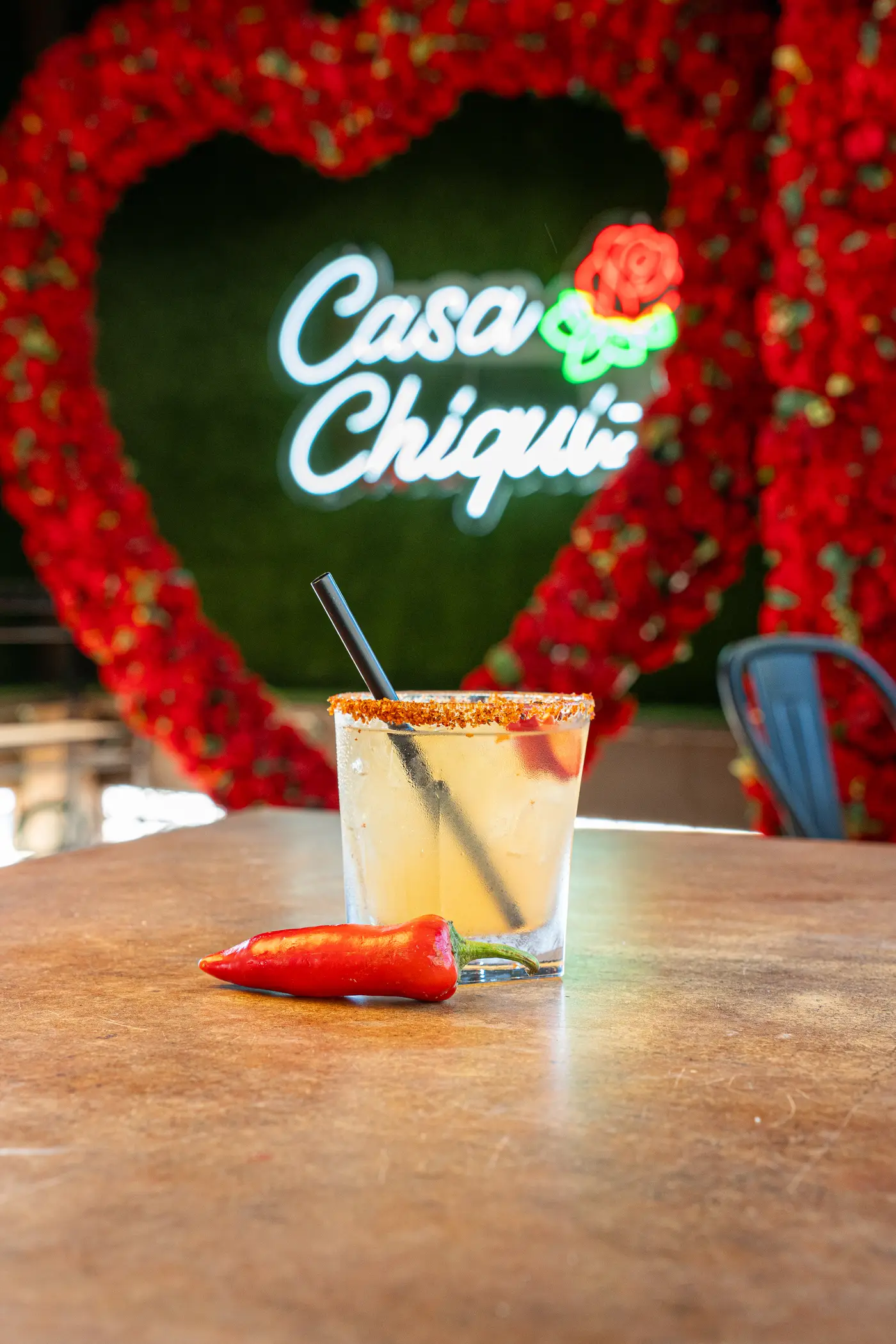 Chile-rimmed margarita in front of the neon Casa Chiquiz rose-heart photo wall