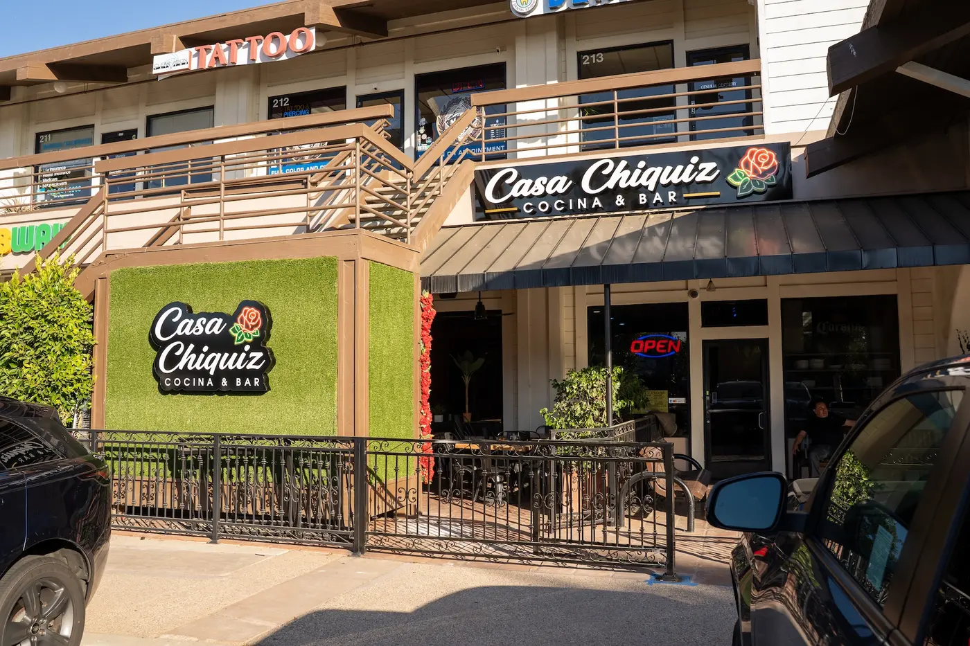 Casa Chiquiz storefront exterior with signage, green hedge wall and patio railing